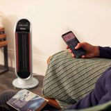 Dimplex Heater Fan Adjustable Thermostat in white with digital remote control held by person on couch