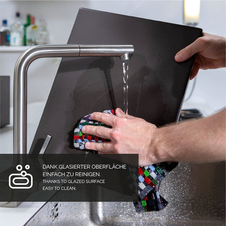Person washing a rectangular pizza stone for oven under kitchen faucet with cleaning cloth