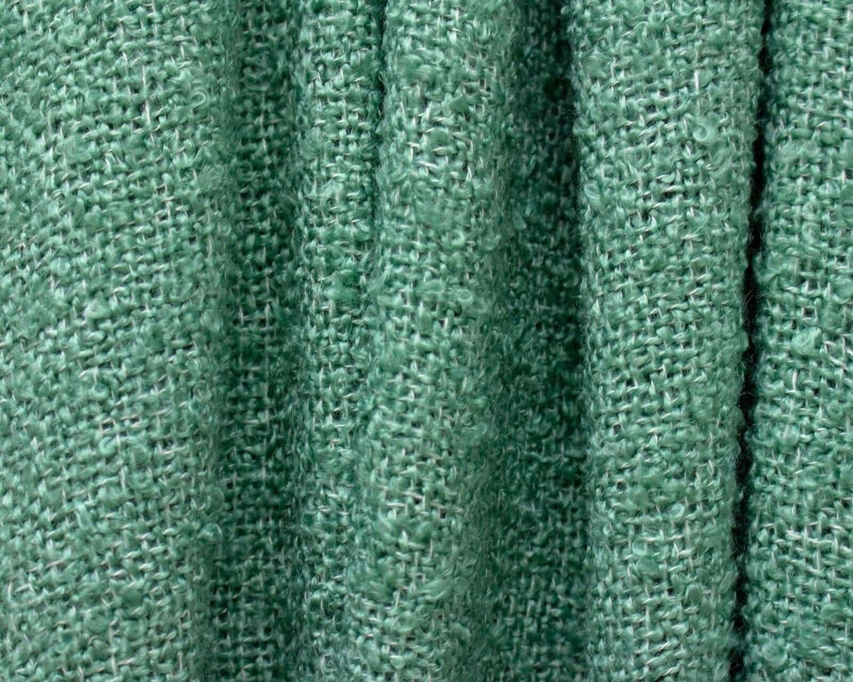 Close-up of green loose weave throw blanket texture showing soft woven fabric fibers