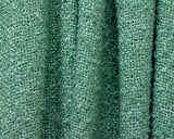Close-up of green loose weave throw blanket texture showing soft woven fabric fibers