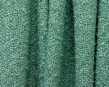 Close-up of green loose weave throw blanket texture showing soft woven fabric fibers