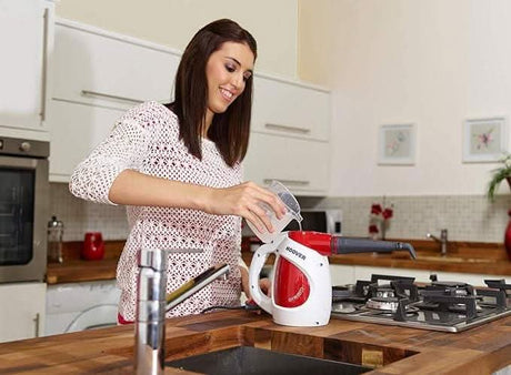 Woman using handheld steam cleaner chemical-free by CLICKK Home Store to clean kitchen stove