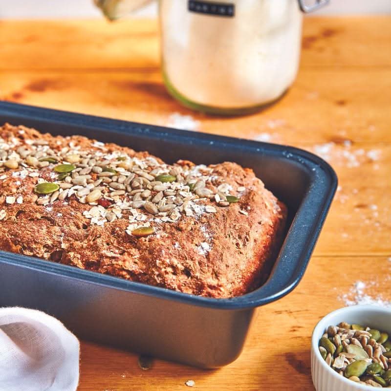 Magimix x De Buyer premium baking accessories set featuring a non-stick loaf pan with freshly baked seeded bread
