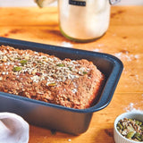 Magimix x De Buyer premium baking accessories set featuring a non-stick loaf pan with freshly baked seeded bread