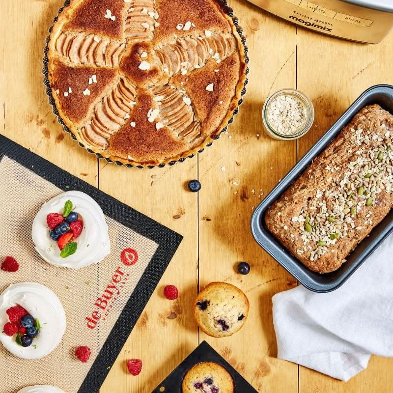 Baked apple tart, bread loaf, muffins, and berry desserts on de Buyer baking mats showcasing premium baking accessories set by Magimix x De Buyer
