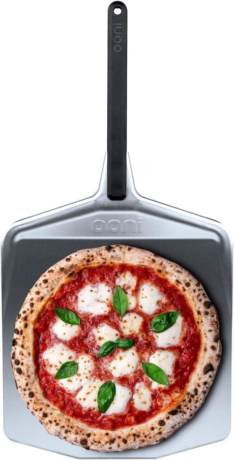14 inch pizza peel with black handle holding a freshly baked pizza topped with mozzarella and basil