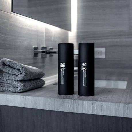 CLICKK Home Store daily thickening shampoo bottles next to gray towels in a modern bathroom setting
