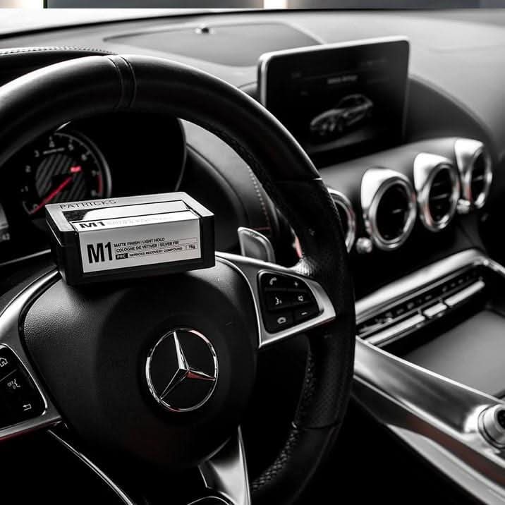 Patricks M1 light hold gel box placed on the steering wheel inside a luxury car interior