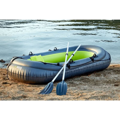 Inflatable family boat in gray with green interior and paddles on the beach by the water