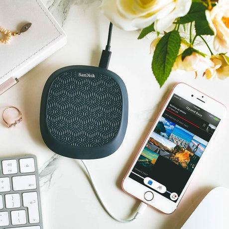 SanDisk iXpand charging base placed next to a smartphone and keyboard for convenient charging and file transfer