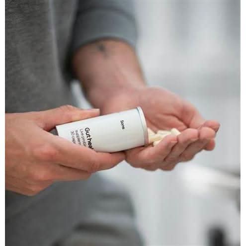 Person holding and pouring gut health capsules from container showing gut health capsule deals