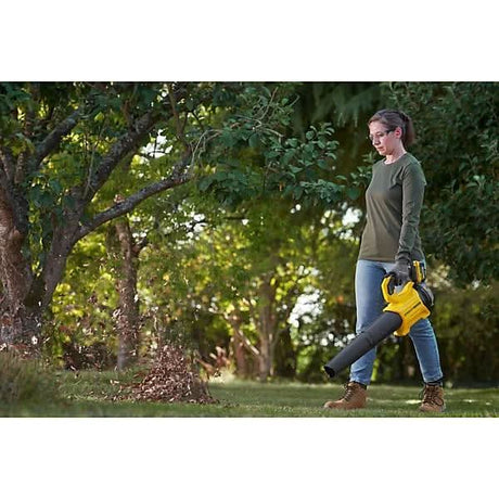 Person using Stanley Fatmax 18V cordless blower to clear leaves in a garden