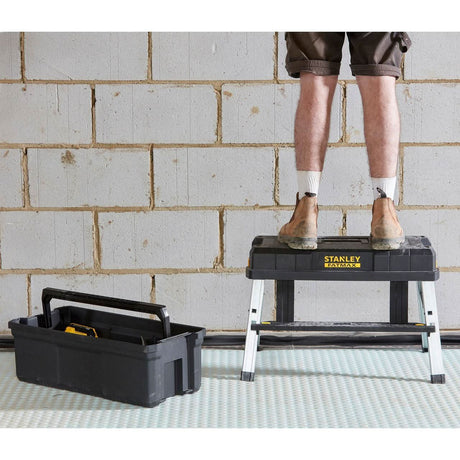 Stanley FatMax tool box open on floor next to person standing on matching step stool in work boots