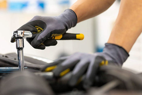 Person wearing gloves using Stanley socket set 72 tooth ratchet wrench to tighten a bolt in an engine