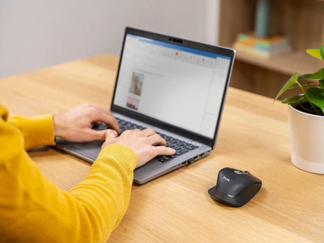 Rechargeable wireless mouse by CLICKK Home Store on wooden desk next to laptop with person typing
