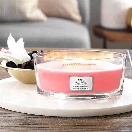 WoodWick Ellipse candle in melon and quartz rose scent with wooden wick burning on a marble tray
