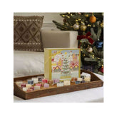 Yankee Candle advent calendar with assorted scented candles displayed on a wooden tray near Christmas tree