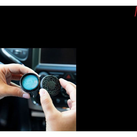 Hands holding Yankee Candle Midsummers Night car fragrance in a car air vent holder